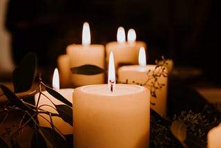 Beautiful image of 6 glowing candles in a dim lighting surrounded by branches.