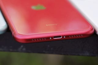 A red iPhone with a lightning connector that won’t be allowed on new devices in the future.