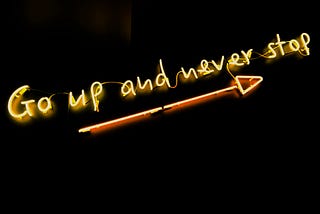 Go up and never stop written in form of a neon sign with an arrow pointing upward.