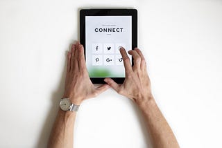 ipad with the words ‘Connect’ displayed on screen and hands reaching out to press onscreen icon.