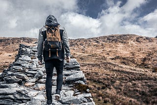 person with a backpack walking up steps