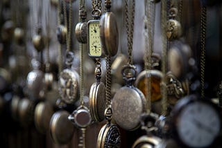 A wall of antique pocket watches to suggest time and people who run late.