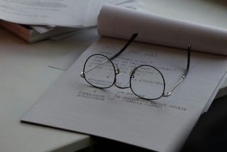 A pair of glasses laying on top of a notepad