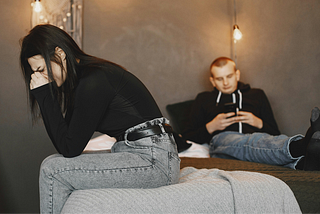 A man being unconcerned while using his phone beside his crying girlfriend on the bed is one of the signs of a narcissistic partner.