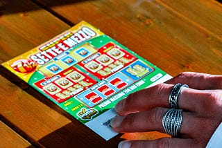 Hand touching jackpot tickets on a wooden surface.
