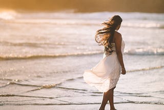 Woman walking alone on the sea shore.