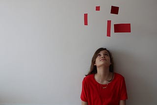 Picture of a girl looking at pieces of red paper above her head