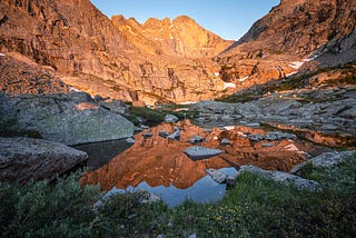 A majestic mountain reflected in an alpine lake at sunrise.