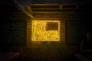Yellow neon lights stating, “STAY HYDRATED”