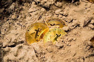 Bitcoin “coins” uncovered from dirt. A metaphor for “mining” bitcoin.