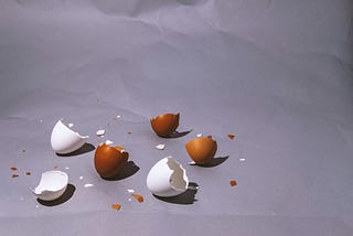 Brown and white, broken eggshells, scattered over the floor.