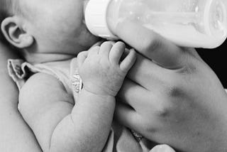A baby drinking milk out of a feeding bottle
