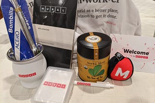 Photo of an assortment of MURAL branded swag, including the materials needed to make yerba mate tea.