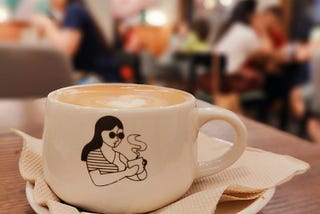 Single woman drinking coffee alone at a cafe full of people