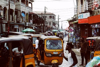 Busy street in downtown Lagos island with yellow keke NAPEPs and pedestrians