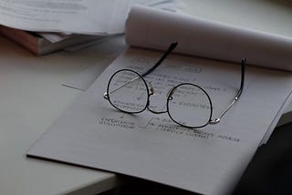 a pair of wire-rimmed glasses lying on a notepad