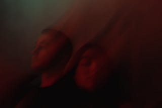 Two people in a blurred background with colour streaming away from their faces.