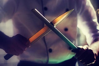 A chef sharpening two knives