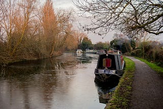 an english canal showing a narrowboat and trees