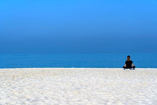 Someone meditating on a beach.