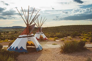 Two colorful Native American teepees near a road