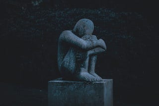 Statue that is crouched and looks like it is crying