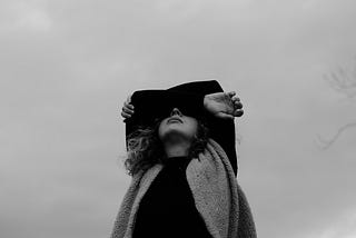 a gray photo of a women with her arms crossed above her head, feeling deep sadness and sorrow and grief.