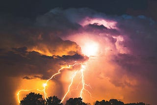 a storm at night- you can see the lightning bolts streak across the clouds in the sky. Oranges and pinks.