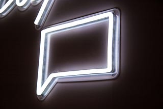 An image of a neon sign in the shape of a speech bubble