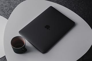A laptop and a cup of coffee lay on a table
