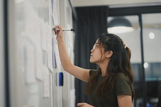 woman writes on whiteboard with a dry erase marker