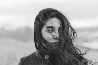 Black and white photo of a young woman, sad, staring into the distance.