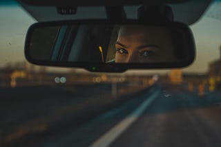 A driver’s eyes visible in a car rear view mirror