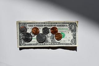 A dollar bill with quarters and cents