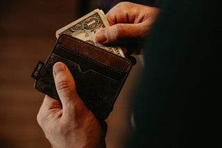 A man removing 1 dollar bills from a wallet