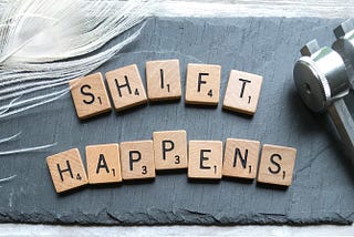 Scrabble letter tiles spelled out as “Shift Happens”