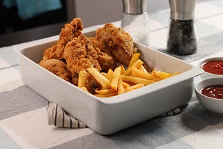 Fried chicken and French fries in a white baking dish