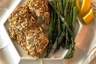 Fish with asparagus on a dinner plate.