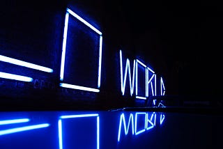 The word “WORLD” spelled in LED lights in a dark room.