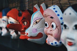 A row of cartoon face masks on a black shelf