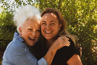 Two women hugging each other and smiling into the camera