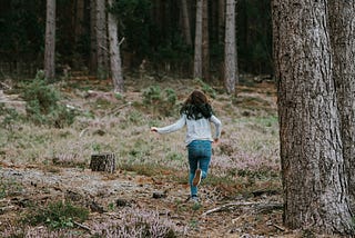 A girl running into the woods.