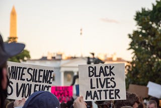 Photo of Black Lives Matter protesters in Washington, D.C. — 2 signs say “Black Lives Matter” and “White Silence is Violence”