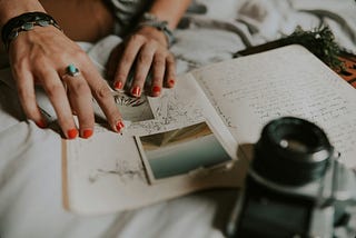 A close-up of a woman’s hands adding photos to her journal