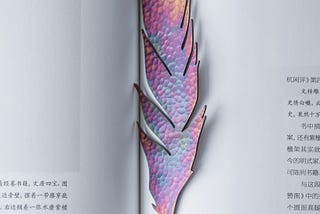 A lavendar and pastel-colored feather marks the pages of a book.