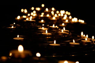 A field of small candles in a sea of black.