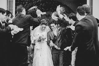 Bride and groom guests throwing confetti. Black and white image.