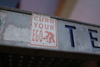 An image of a street sign telling people to ‘curb their ego’.