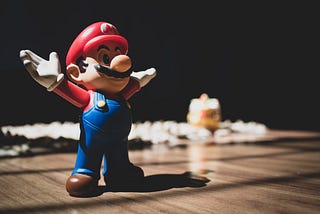 Small figurine of Mario with arms extended out, sitting on a table