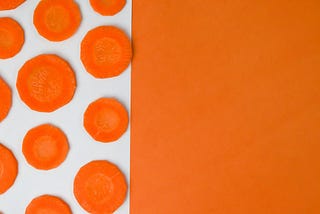 A white and orange background with carrot slices arranged on top